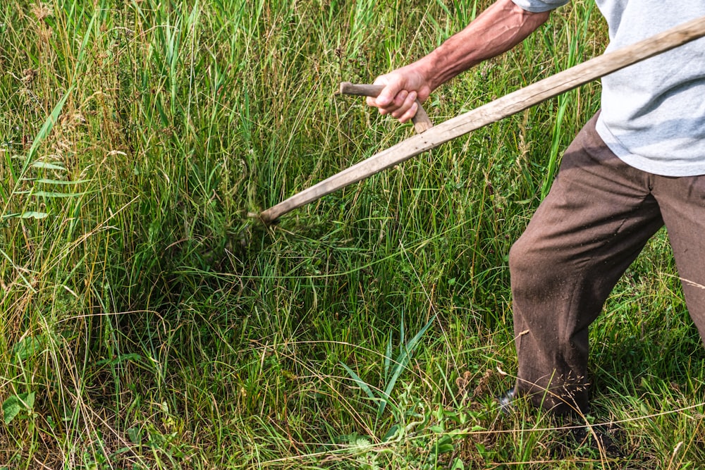 um homem segurando uma vara em um campo de grama alta