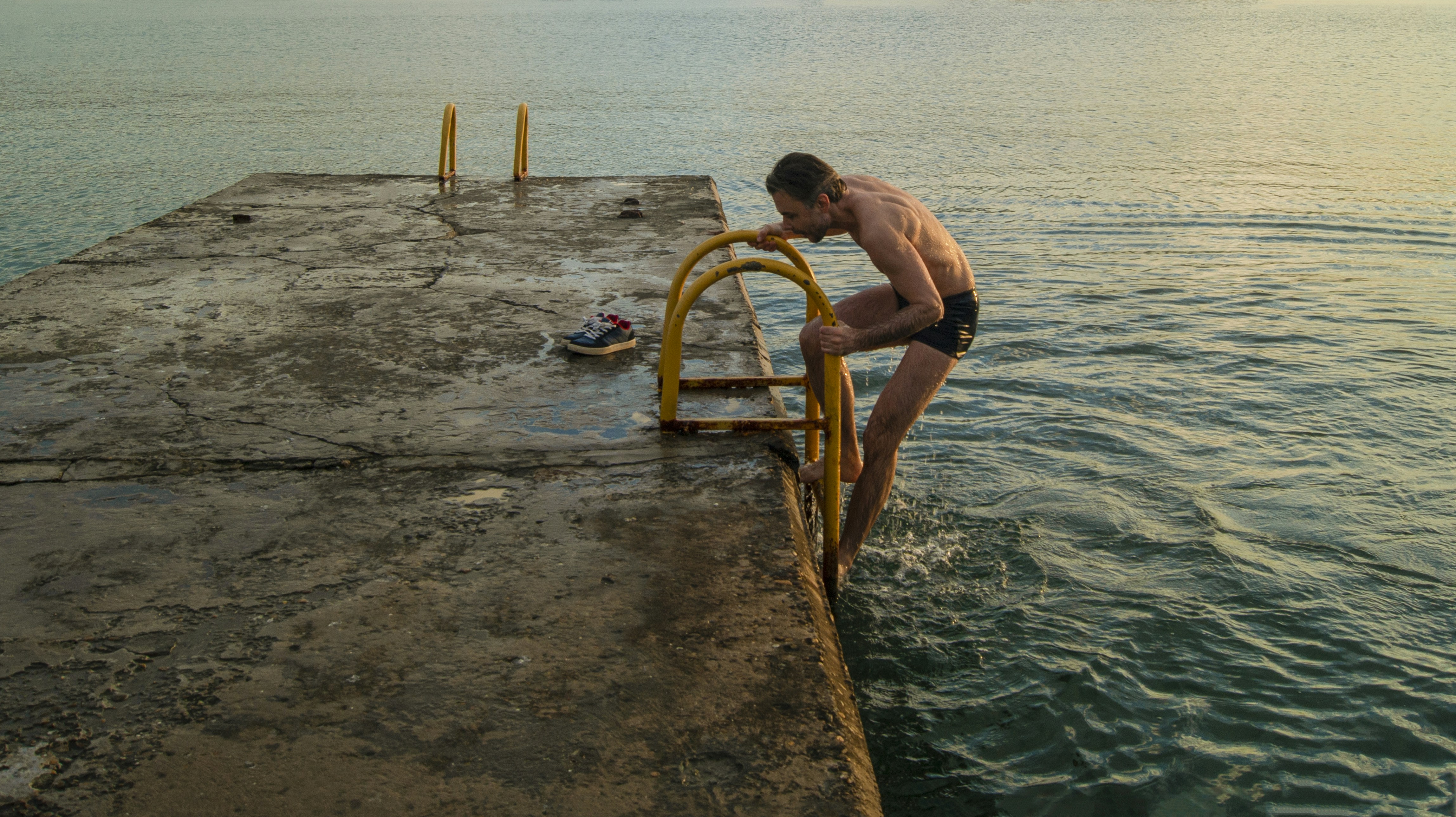 a man standing on a dock next to a body of water