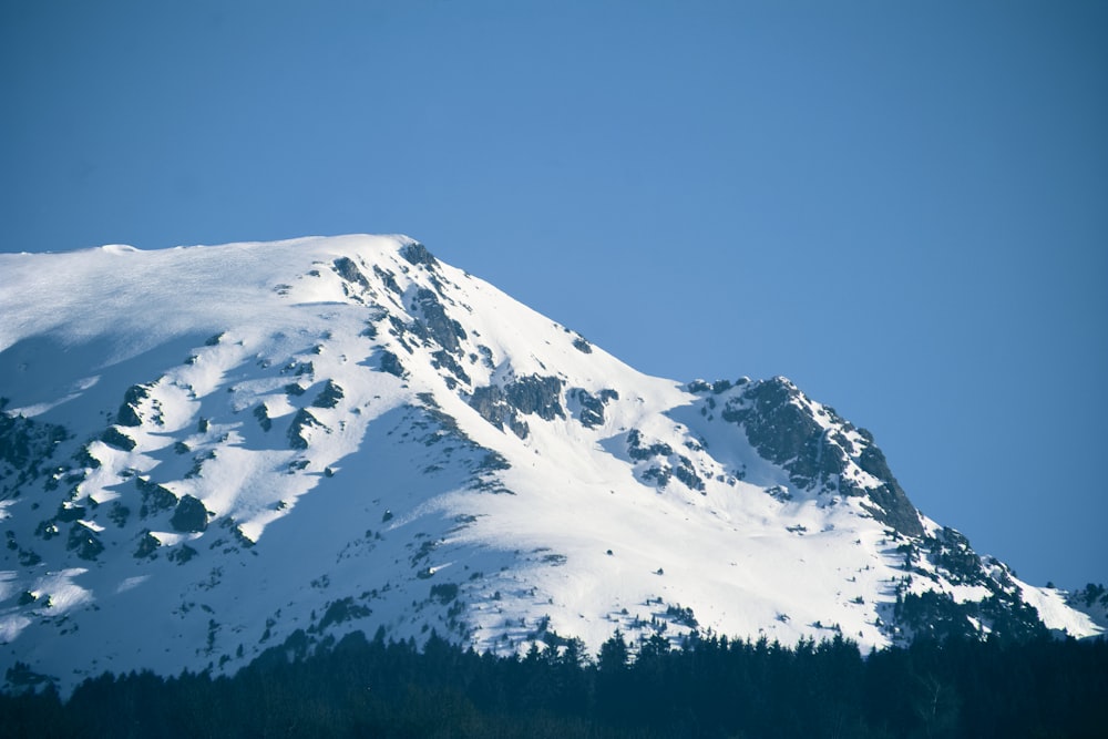 a snow covered mountain with trees below it