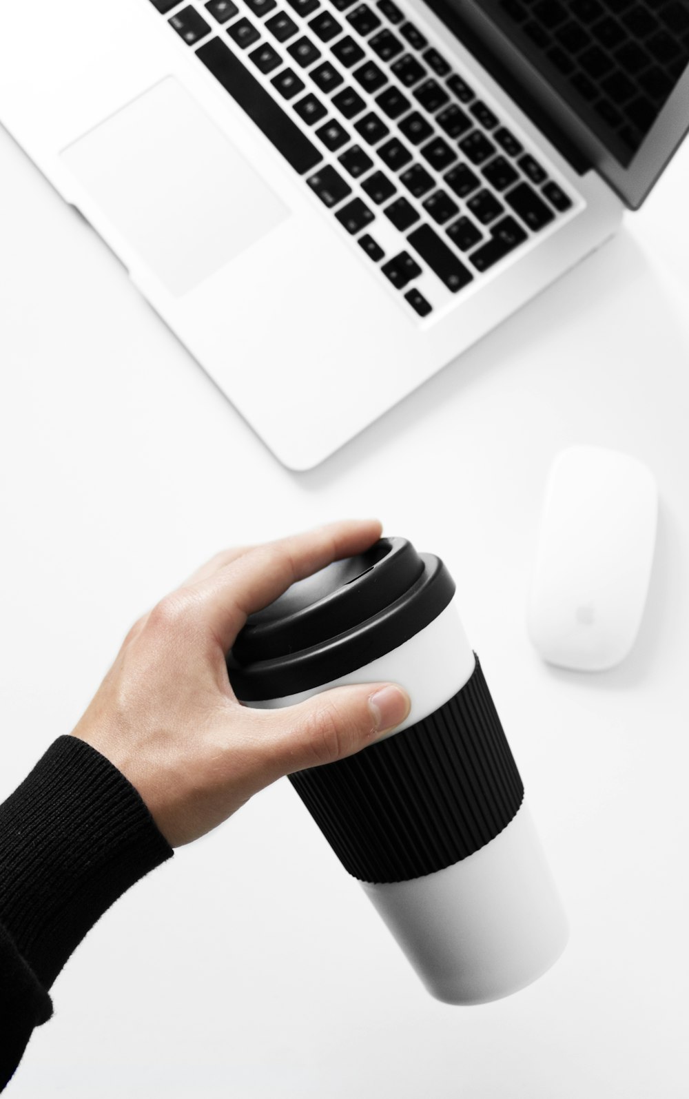 a person holding a coffee cup in front of a laptop
