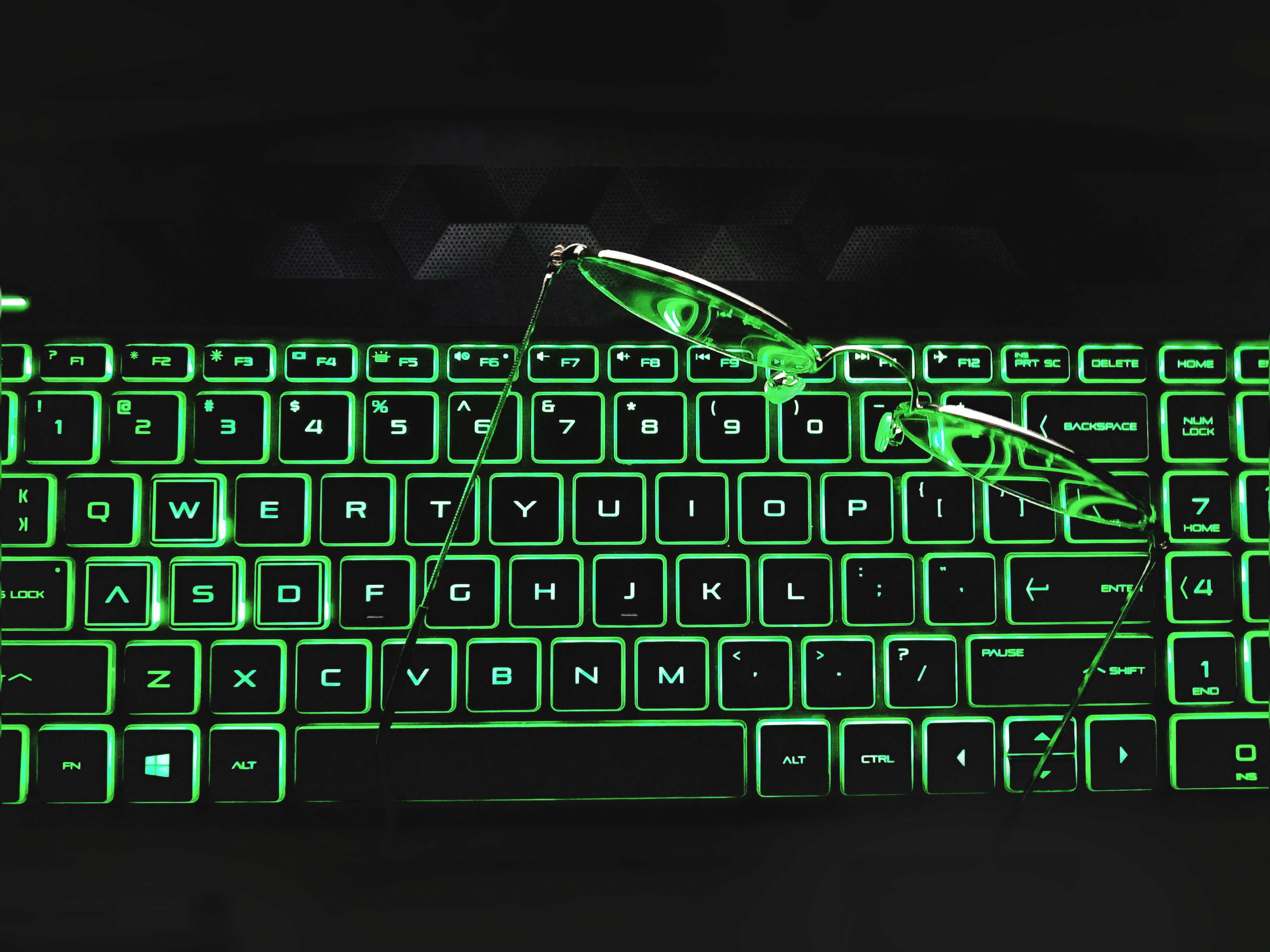 A computer keyboard with a pair of glasses on top of it photo Free