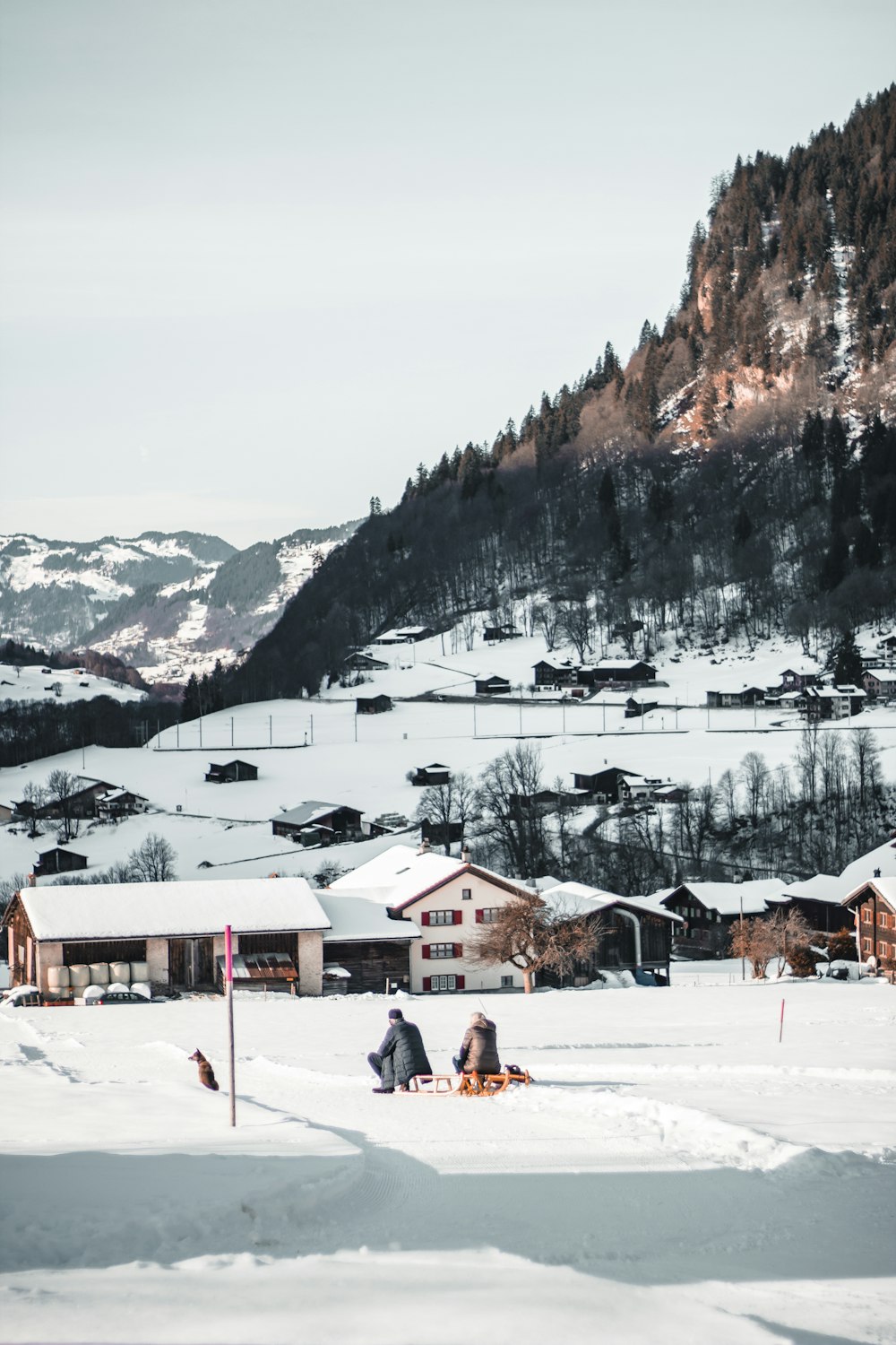 a group of people sitting on top of a snow covered field