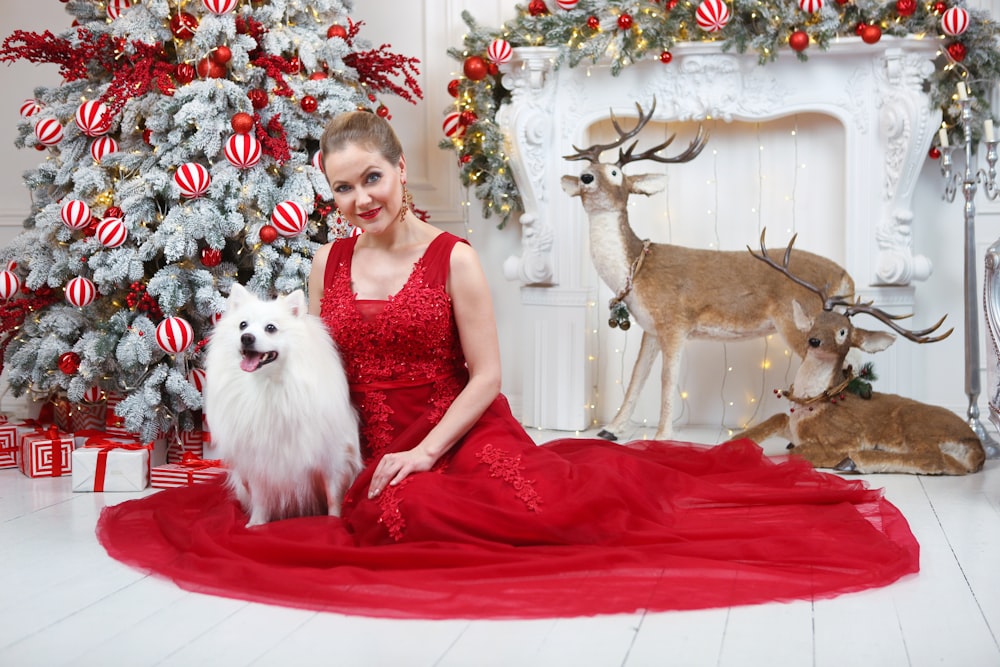 a woman in a red dress sitting next to a white dog