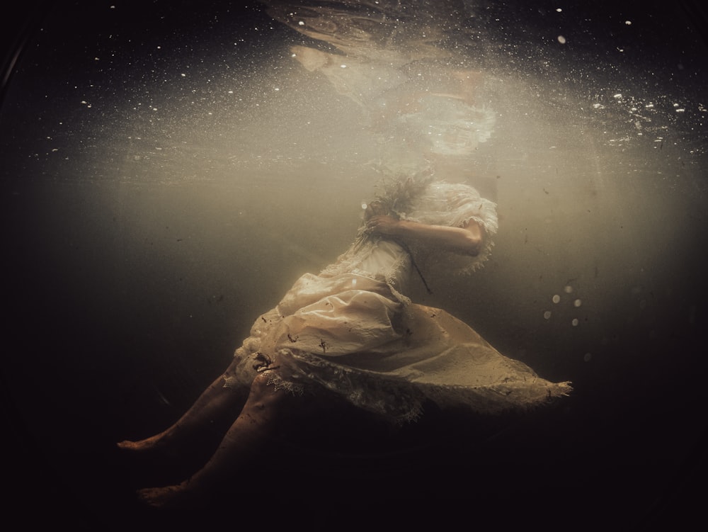 a woman in a white dress under water