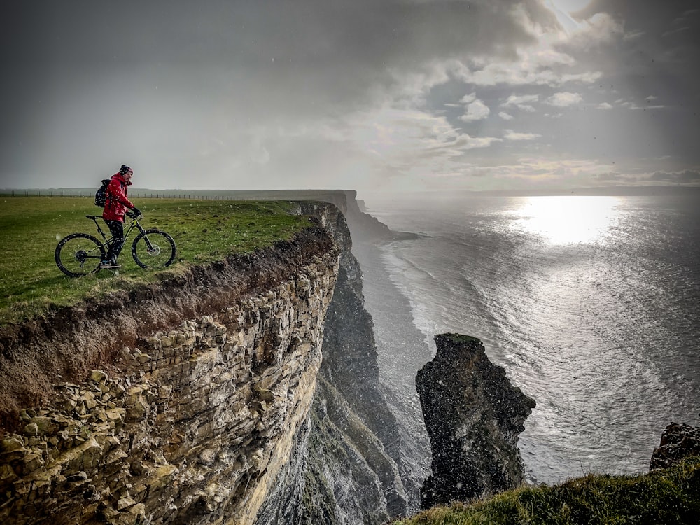 a person riding a bike on the edge of a cliff