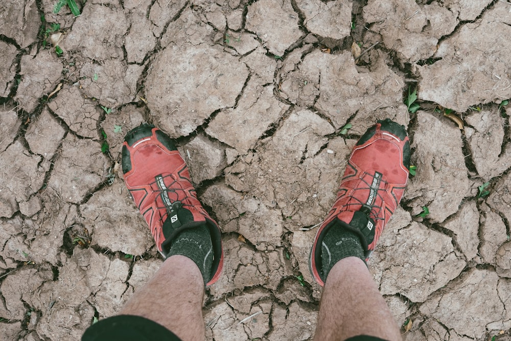 a person wearing red shoes standing on a cracked ground