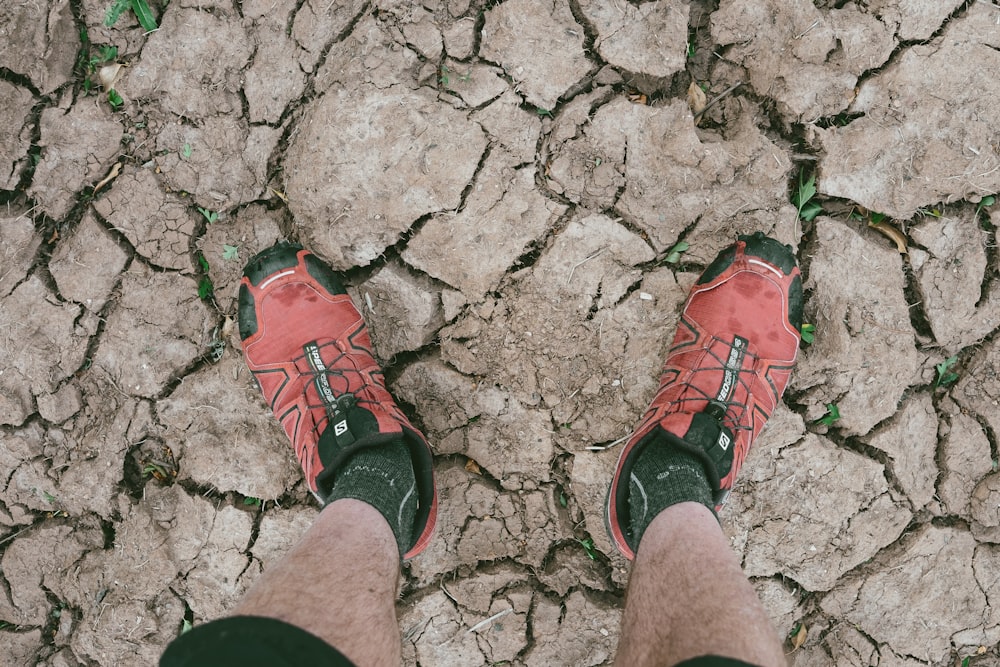 Una persona con zapatos rojos de pie en un suelo agrietado