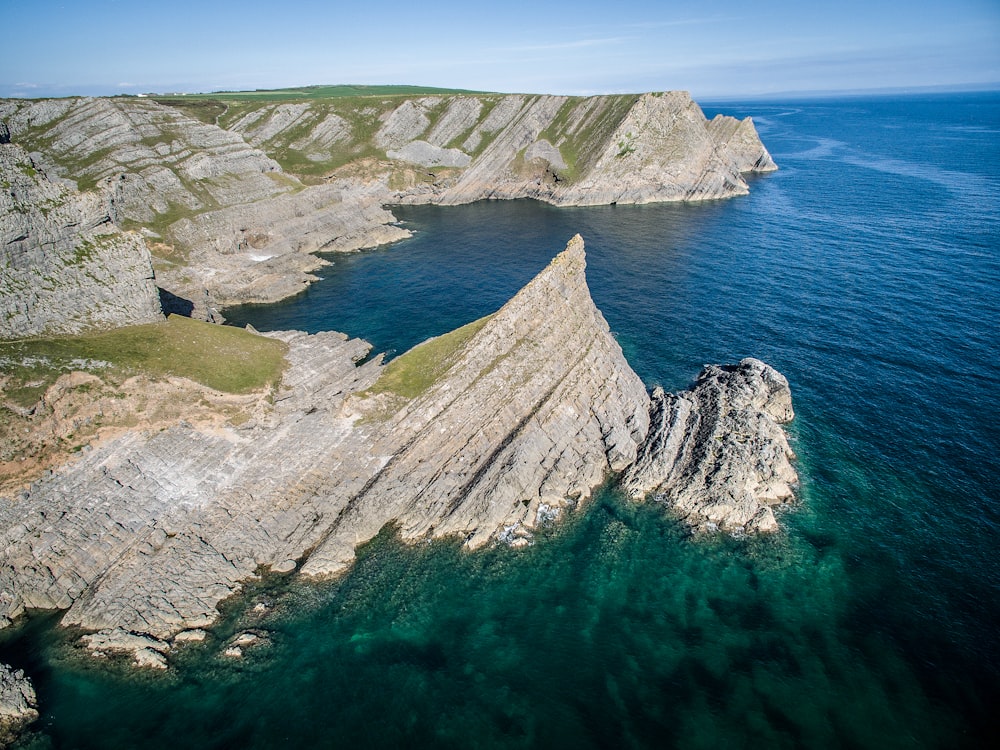 an aerial view of a rocky coastline with clear blue water