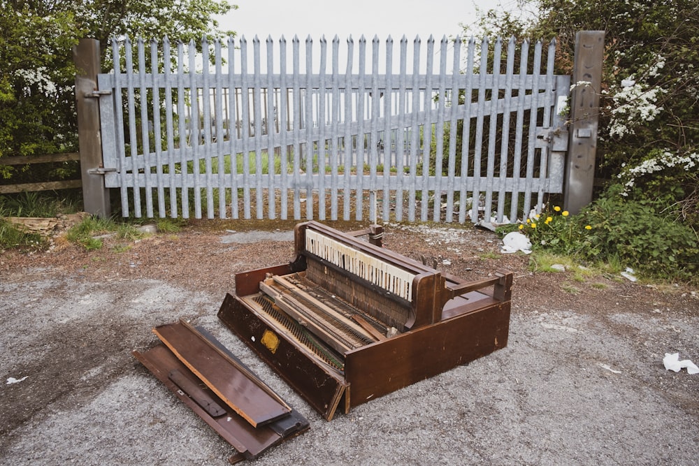 a broken piano sitting in front of a white picket fence