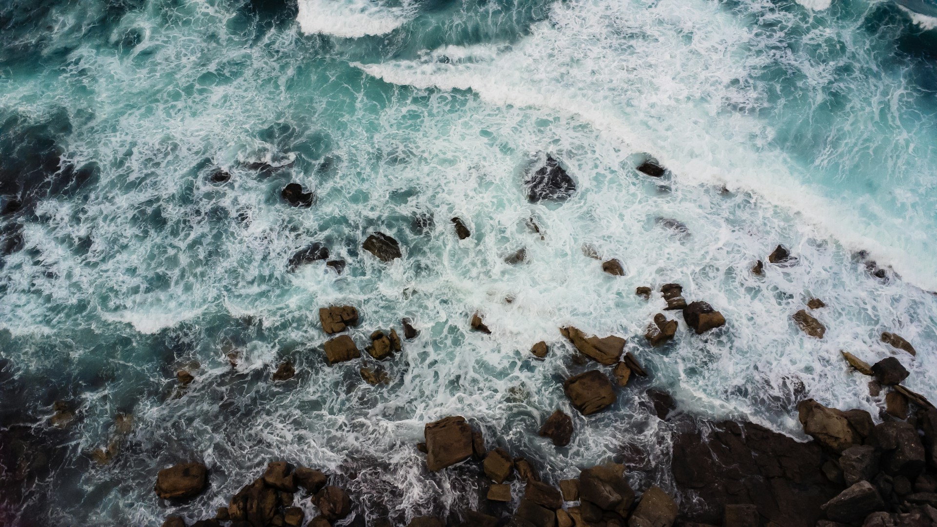 an aerial view of the ocean and rocks