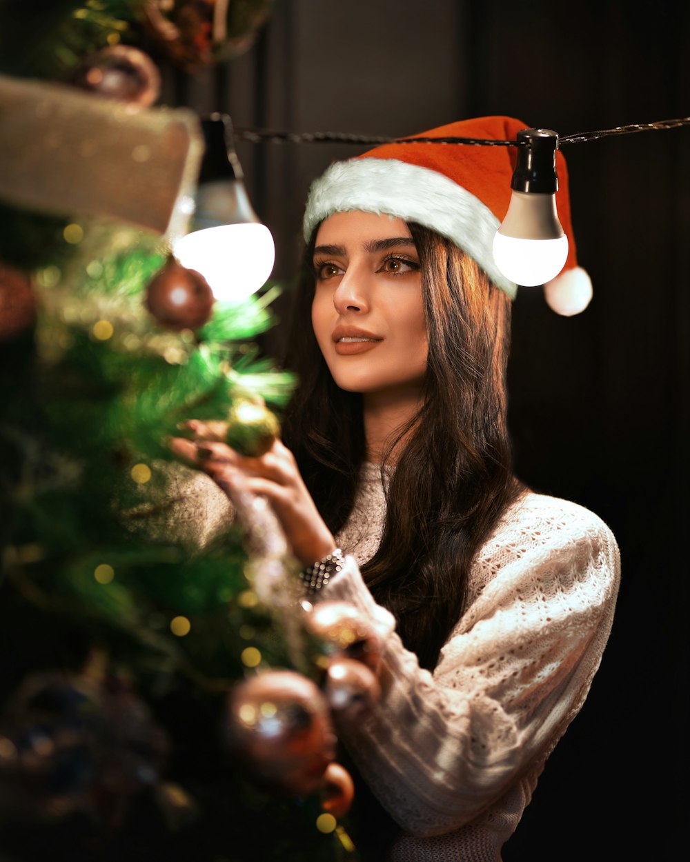 a woman wearing a santa hat next to a christmas tree