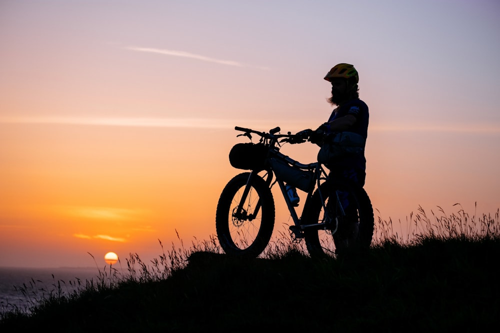 a man standing next to a bike on top of a hill