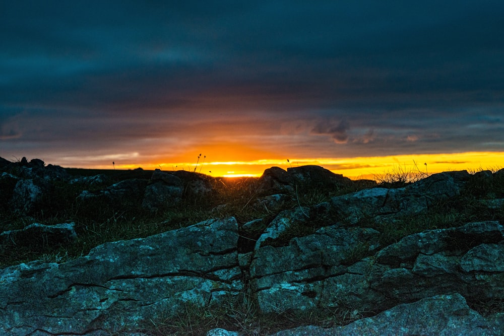 the sun is setting over a rocky hillside