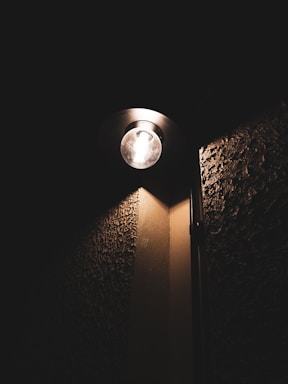 A wall light casting a warm glow on a textured wall.
