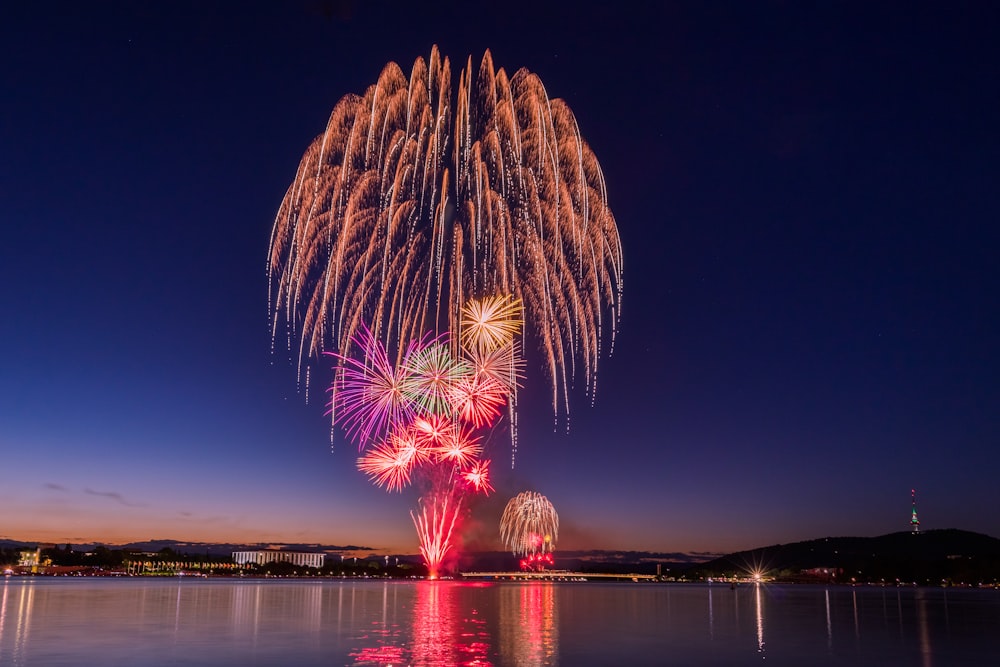 fireworks are lit up in the night sky over a body of water