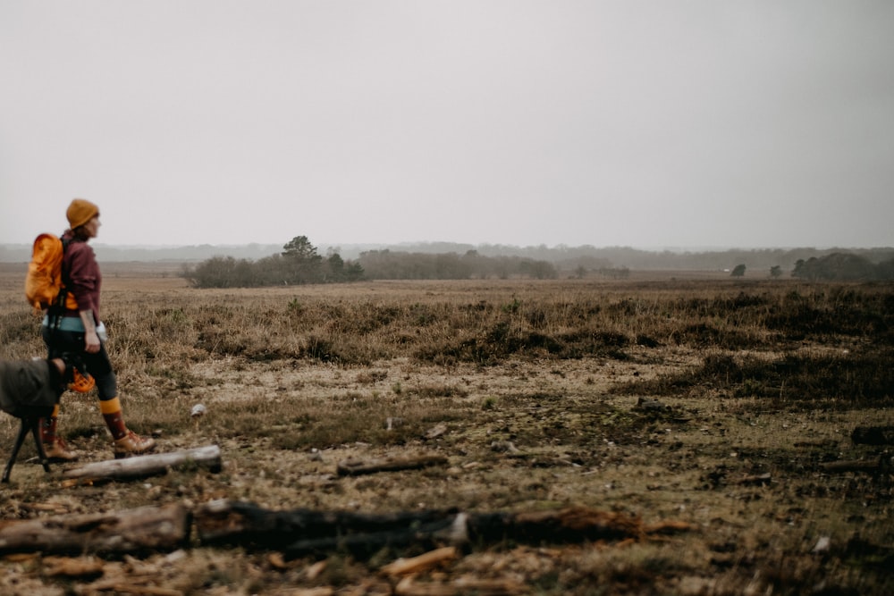 a person walking in a field with a backpack