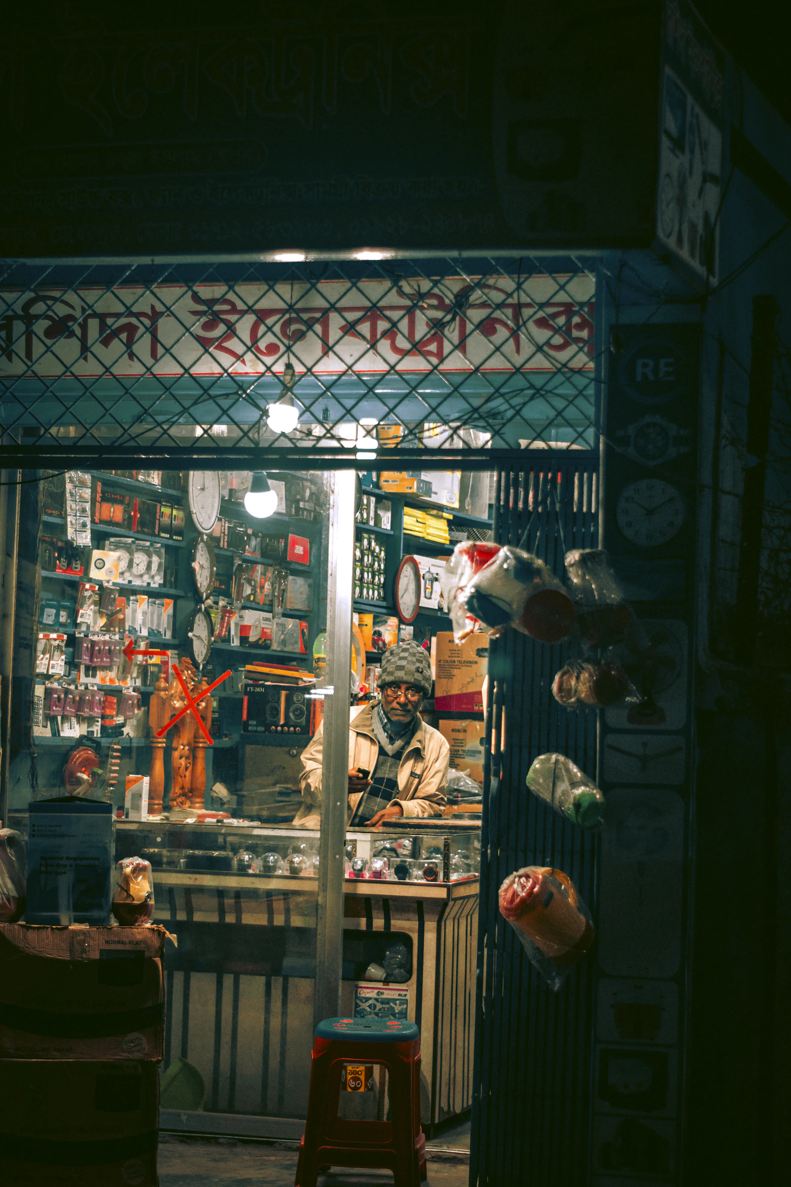 A shopkeeper sitting behind the counter of his shop in the evening
