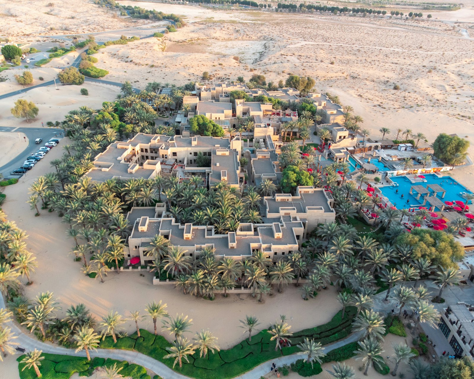 Aerial view of a modern desert resort destination nested among palm groves in golden light
