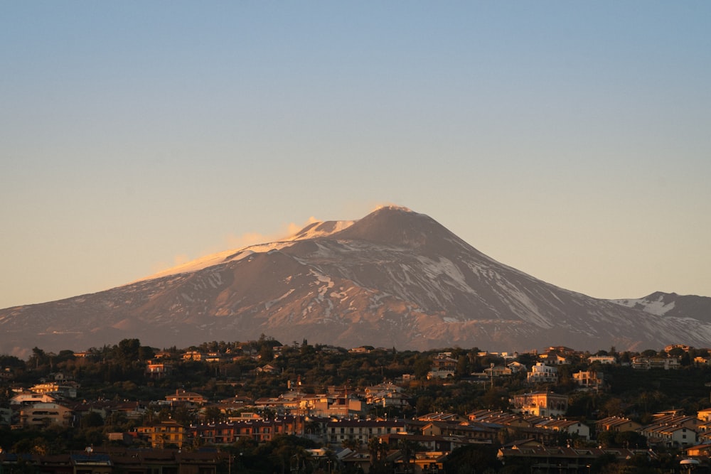 a snow covered mountain towering over a city