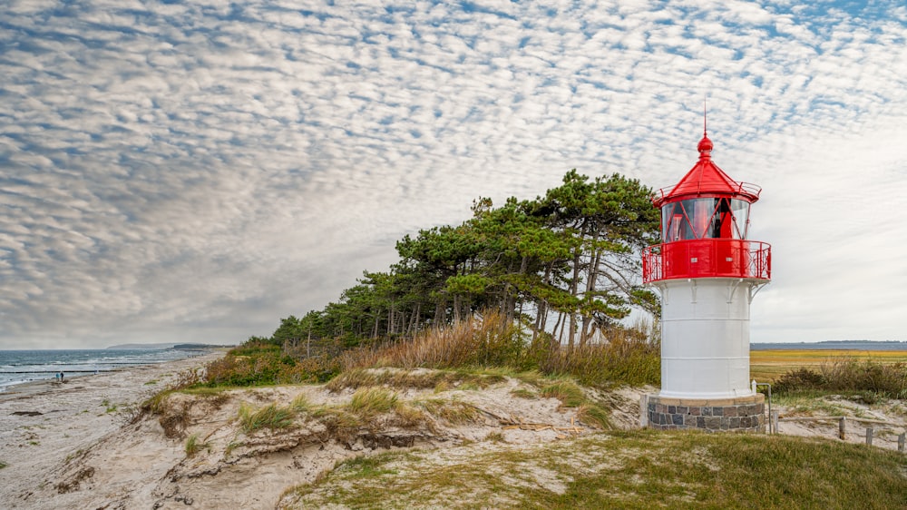 a red and white lighthouse sitting on top of a sandy beach