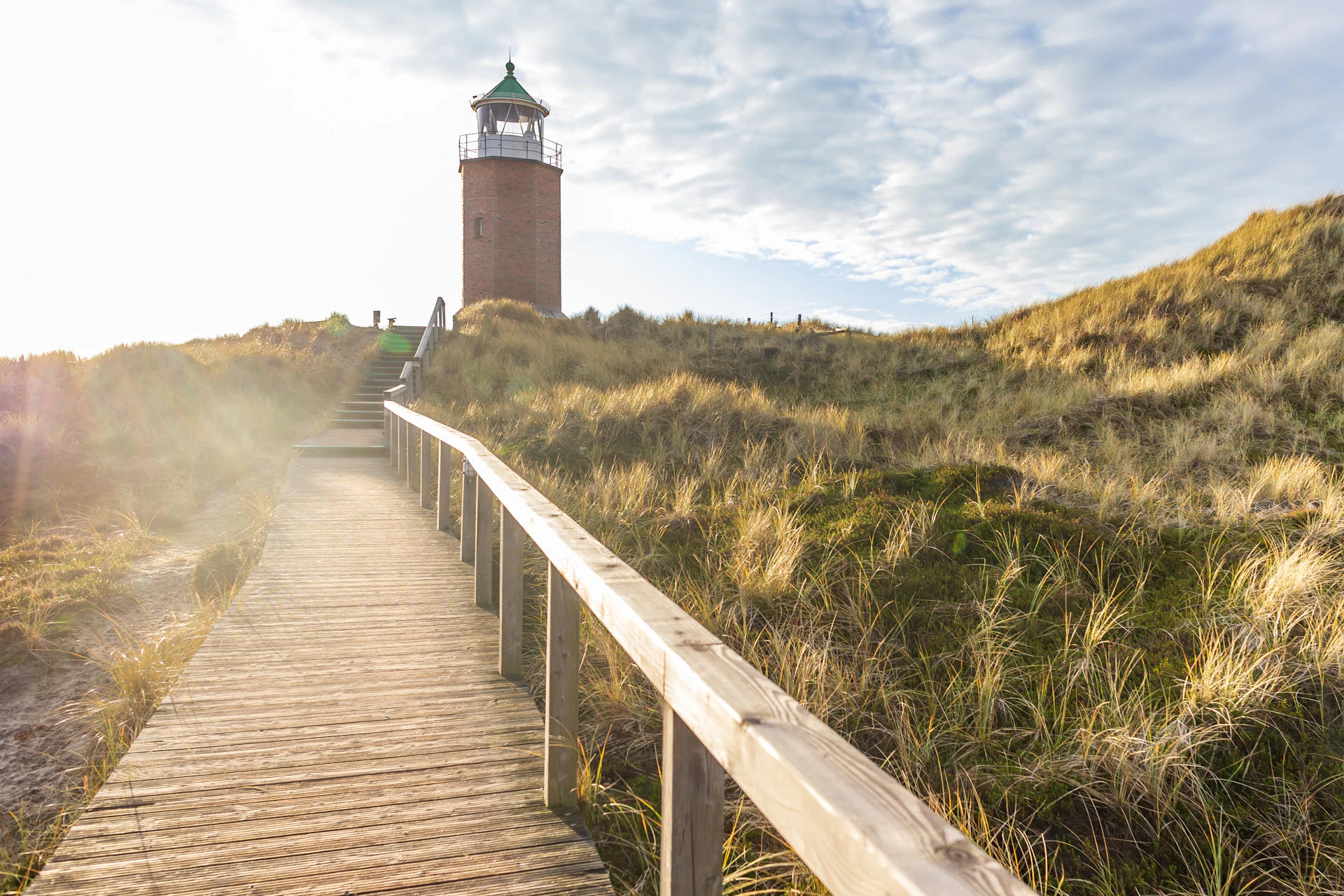 a wooden walkway leading to a lighthouse on a hill