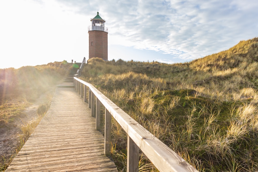 a wooden walkway leading to a lighthouse on a hill