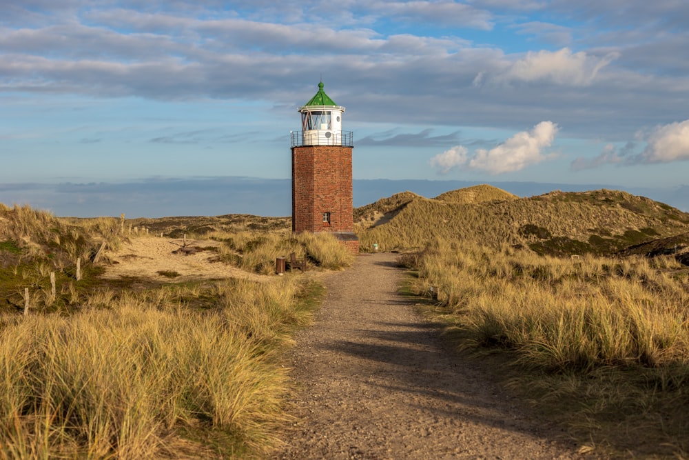 a dirt path leading to a tower with a clock on top