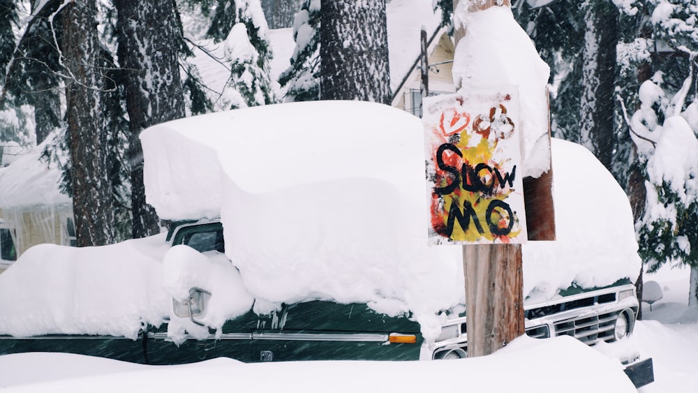 a truck covered in snow next to a sign