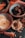 An assortment of dried fruits and nuts is arranged in decorative bowls and scattered on a dark surface. The bowls contain dried apricots, pistachios, and slices of dried pineapple. The intricate patterns on the bowls add an artistic touch to the rustic presentation.