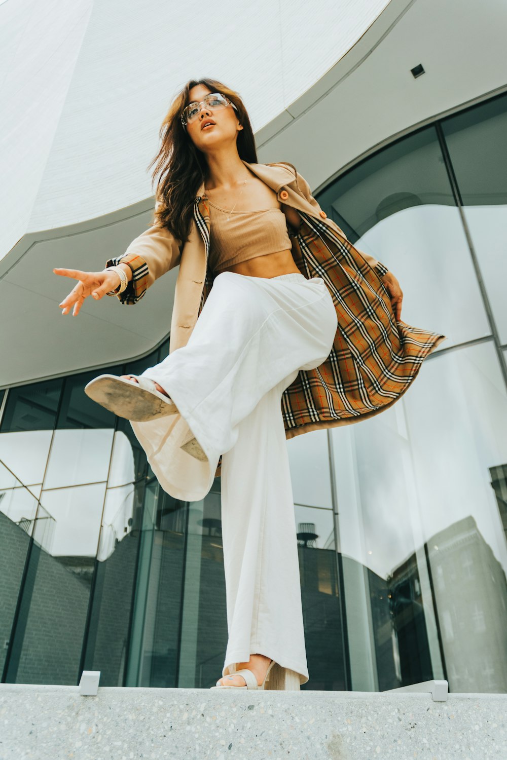 a woman in a tan top and white pants