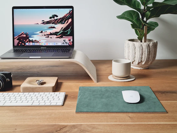 A cozy workspace with a laptop, healthy snacks, and skincare products arranged neatly on a wooden desk.