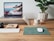 A close-up of a sleek laptop on a wooden desk with a stylish mouse and accessories arranged neatly beside it.