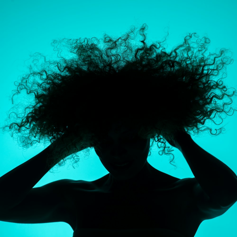 a silhouette of a woman with her hair blowing in the wind