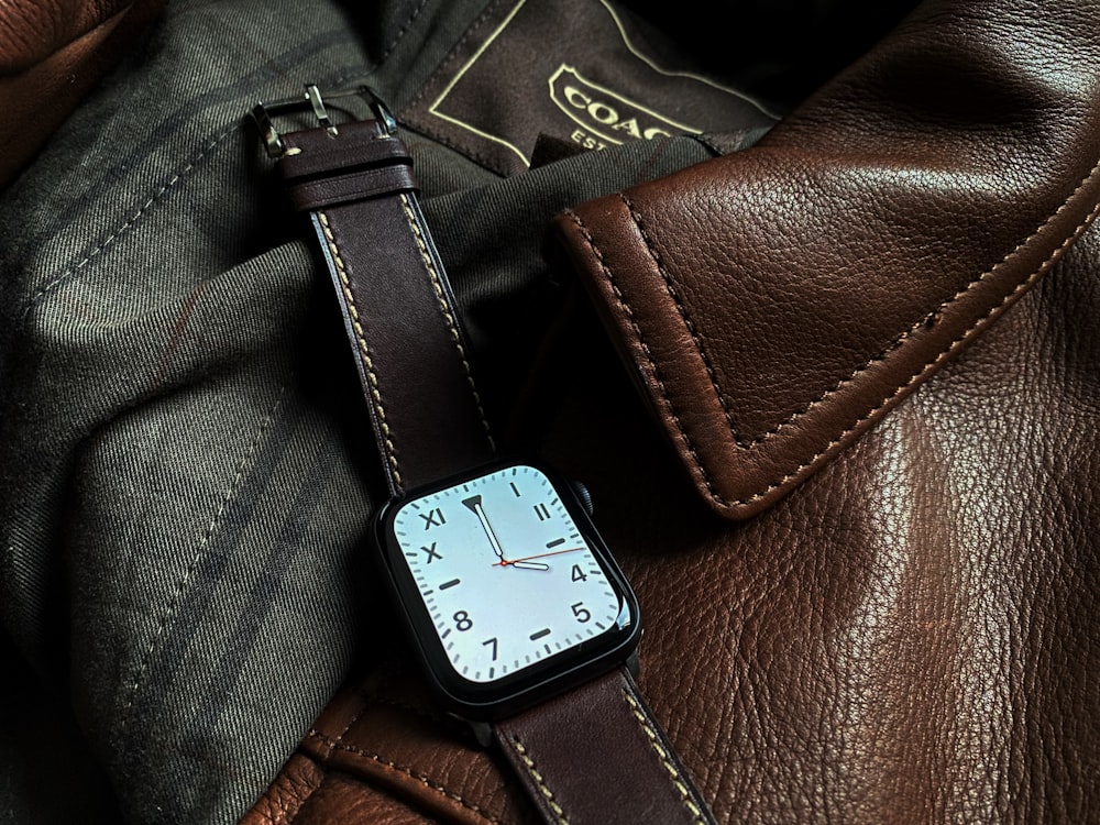 an apple watch sitting on a brown leather bag