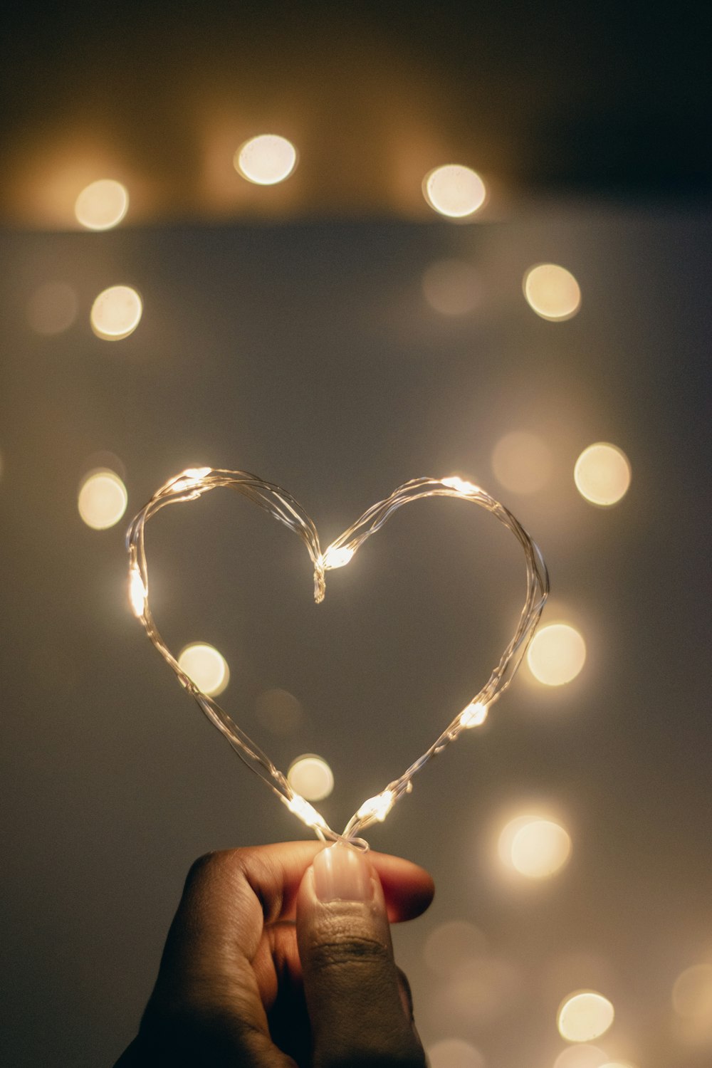 una mano sosteniendo una cadena de luces en forma de corazón