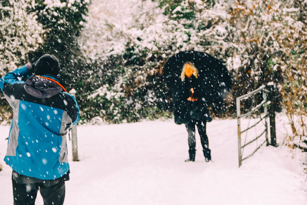 a couple of people walking through a snow covered forest