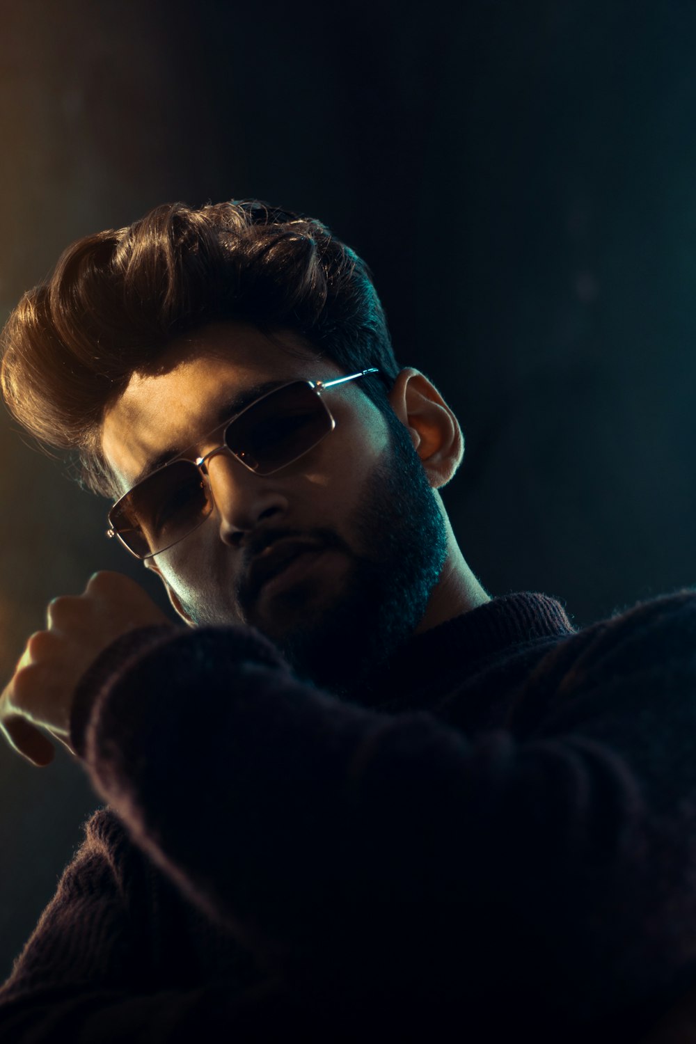 a man with a beard and sunglasses holding a cigarette