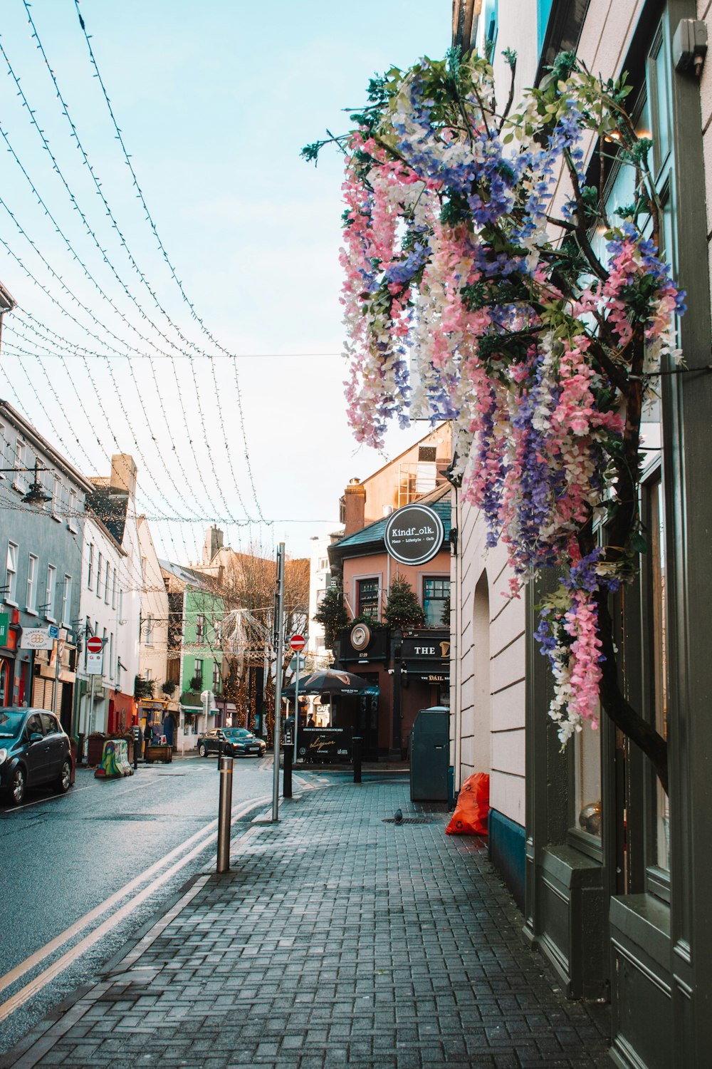 a street with a bunch of flowers hanging from the side of it