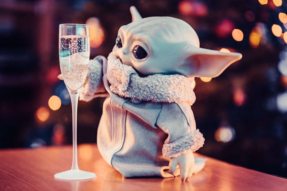 Una statuetta di Baby Yoda che tiene un bicchiere di champagne