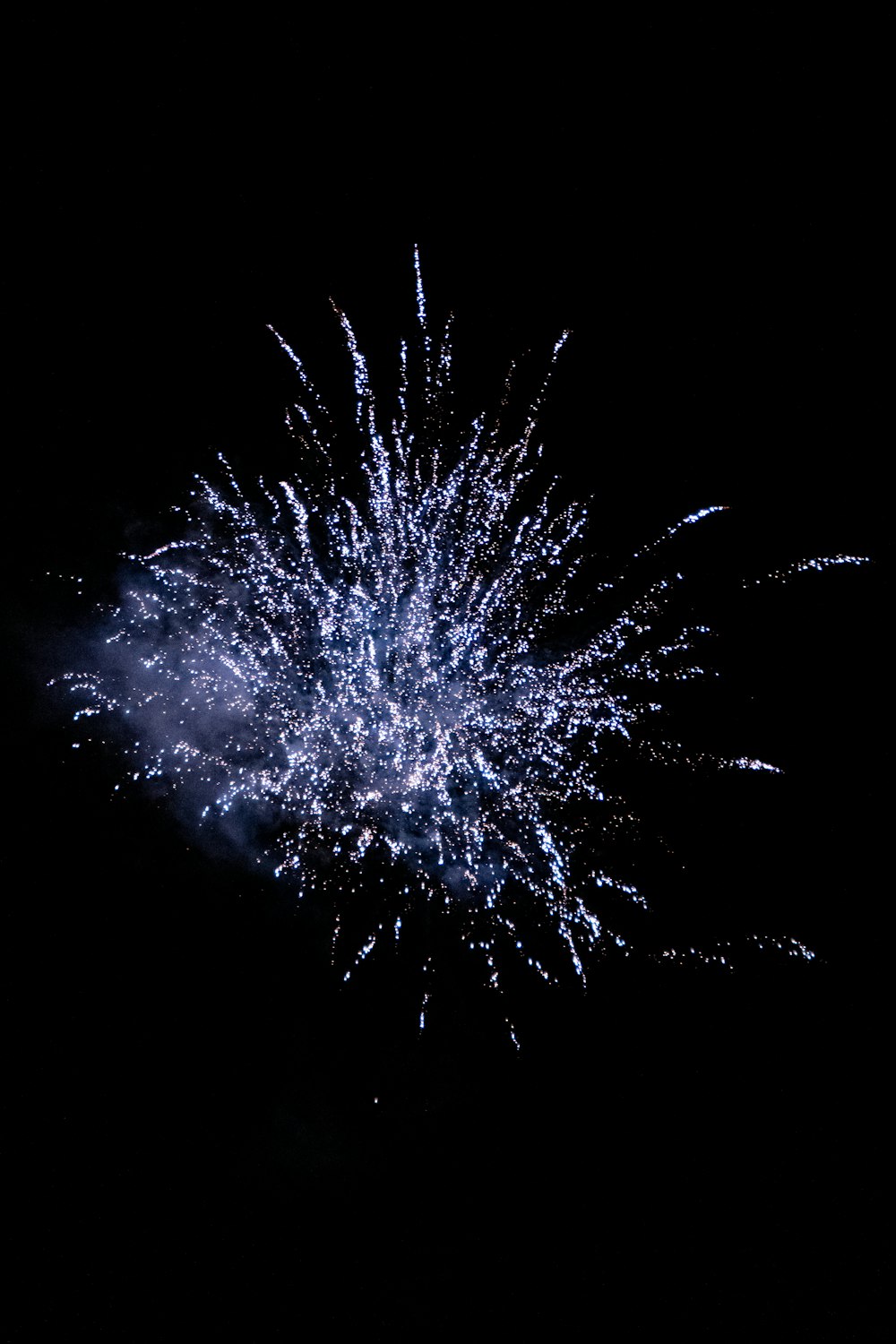 a blue and white firework in the night sky
