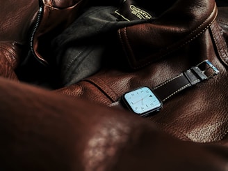 a watch sitting on top of a brown leather bag