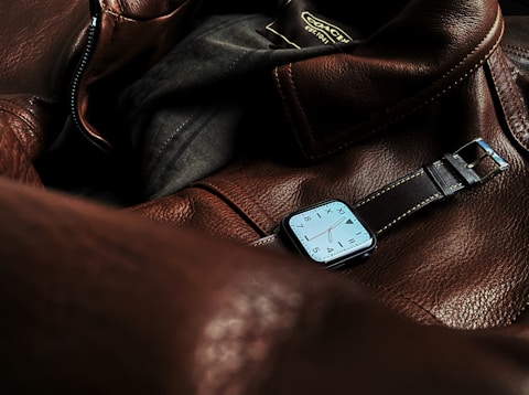 a watch sitting on top of a brown leather bag