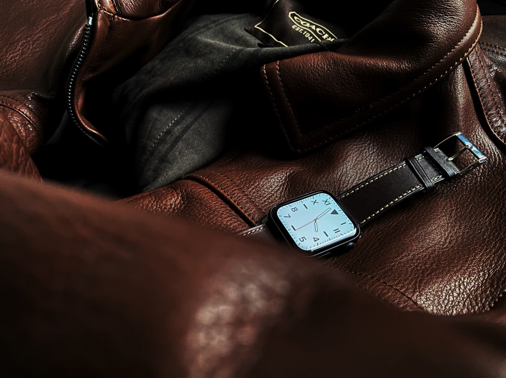 a watch sitting on top of a brown leather bag