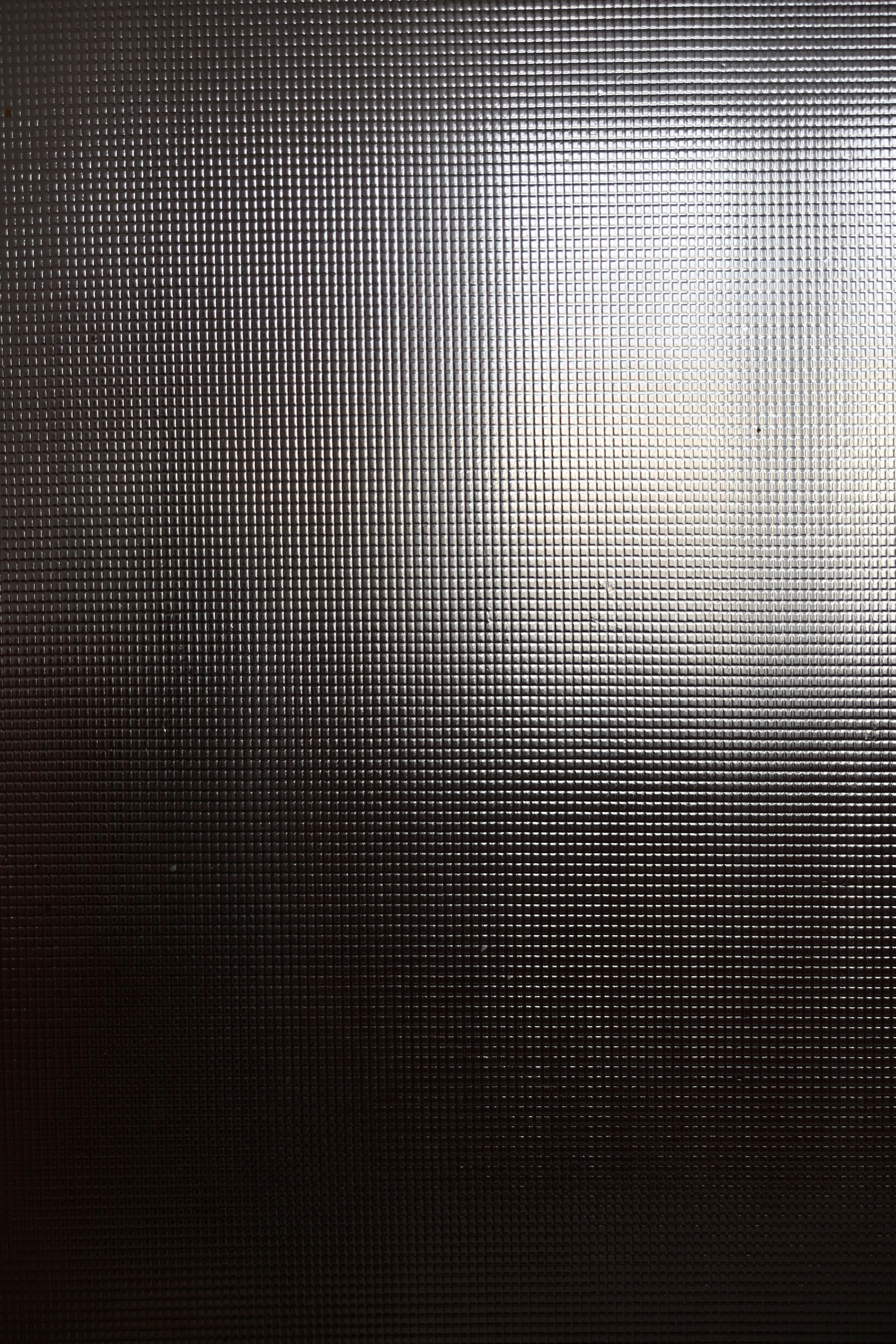 A dark textured metal surface catching a band of light