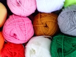 Close-up of colorful yarn skeins spilling out of a woven basket.