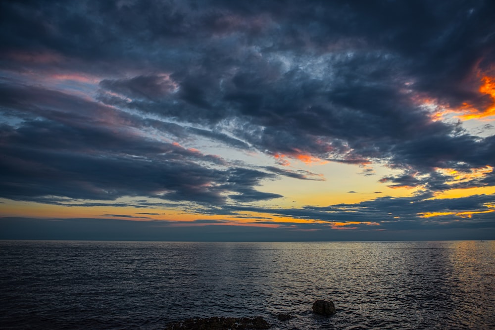 a sunset over a body of water with clouds in the sky