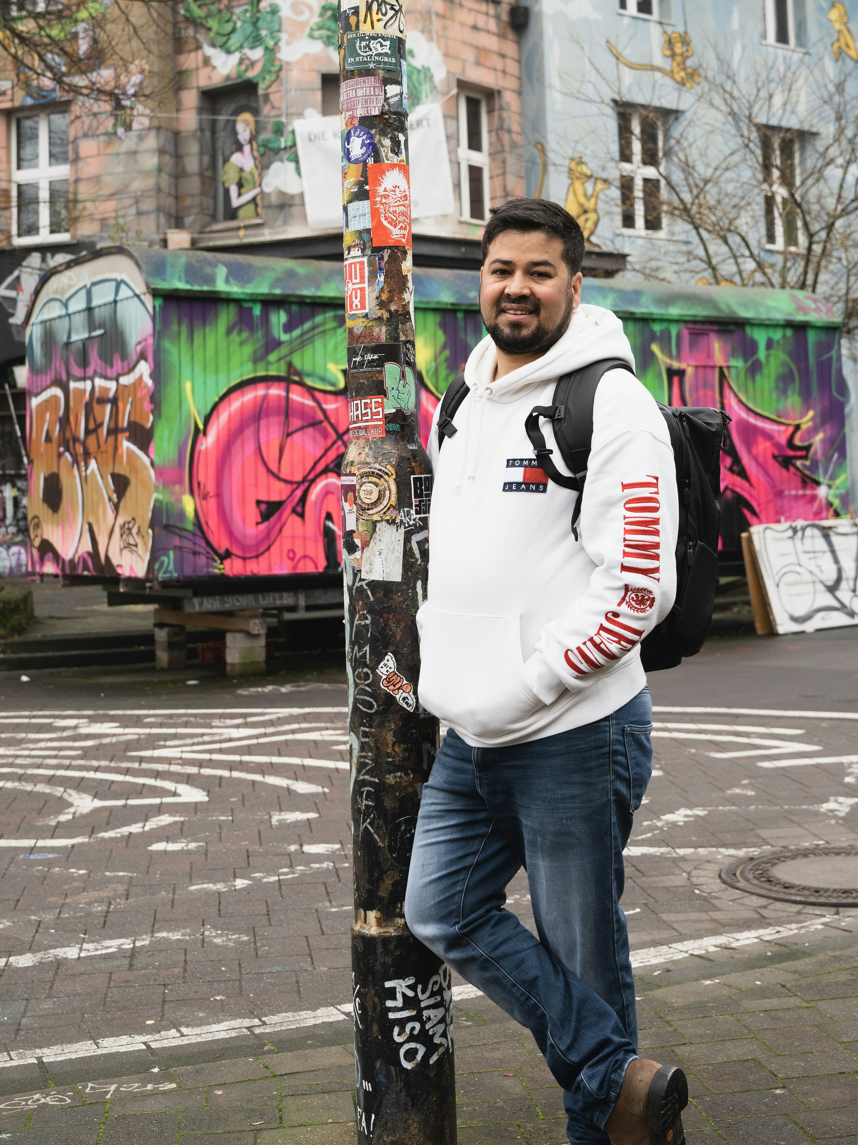 a man standing next to a pole with graffiti on it