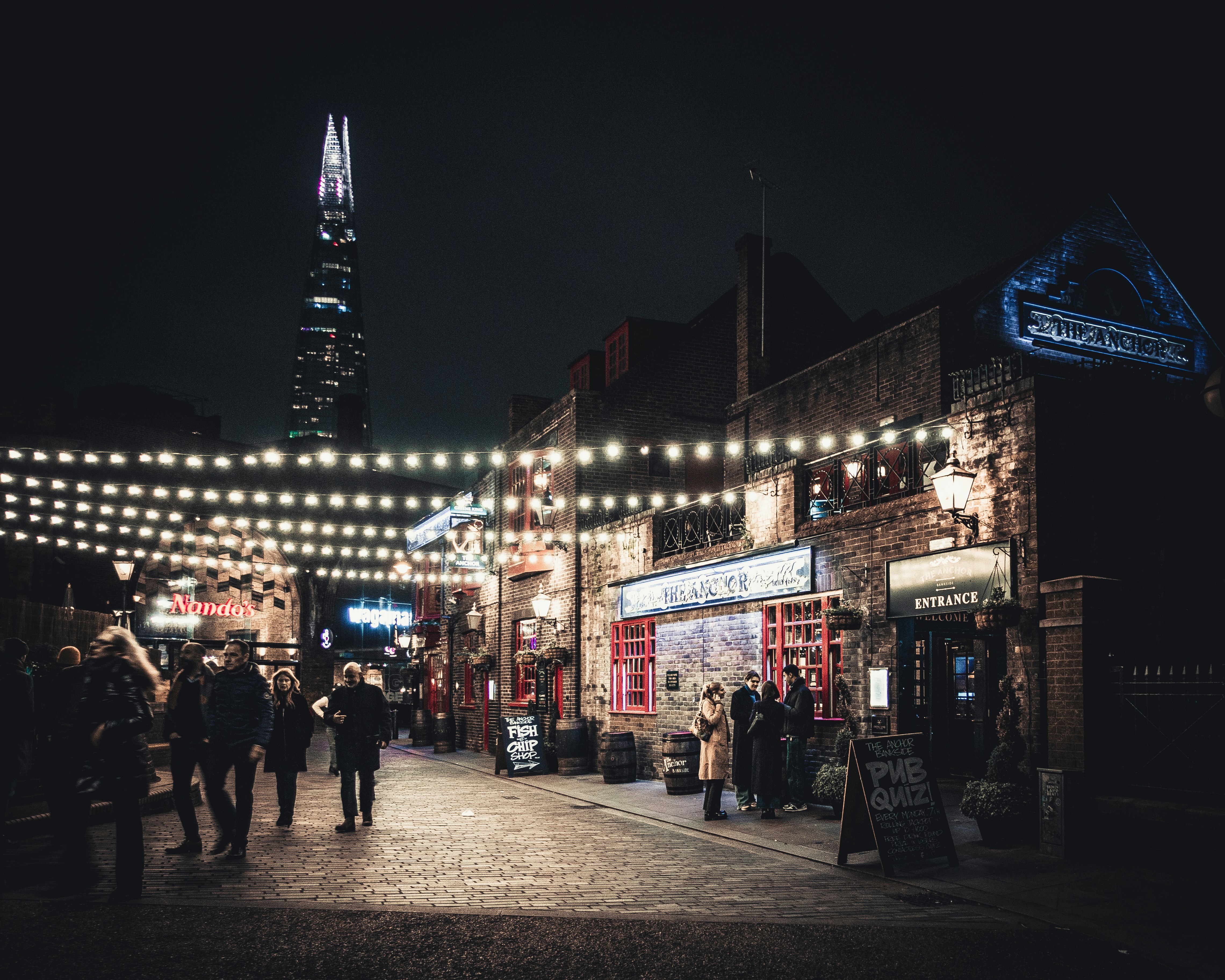 a group of people walking down a street at night