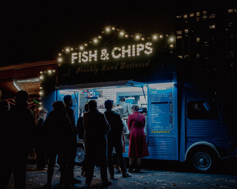 a group of people standing outside of a food truck