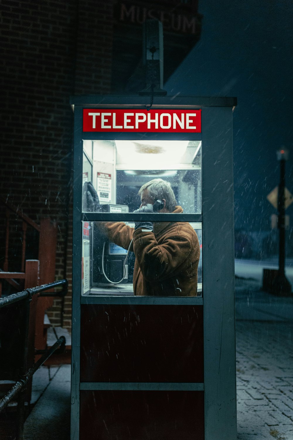 a man is using a telephone booth in the snow